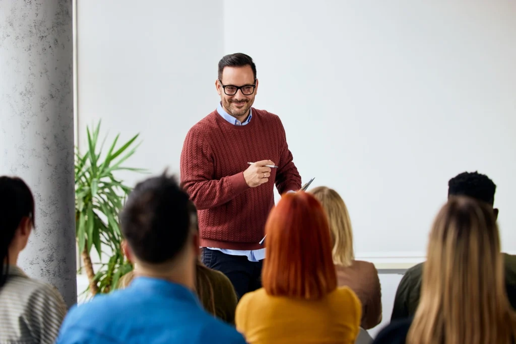 Trainer speaking to a group during a professional training session in a bright meeting room.